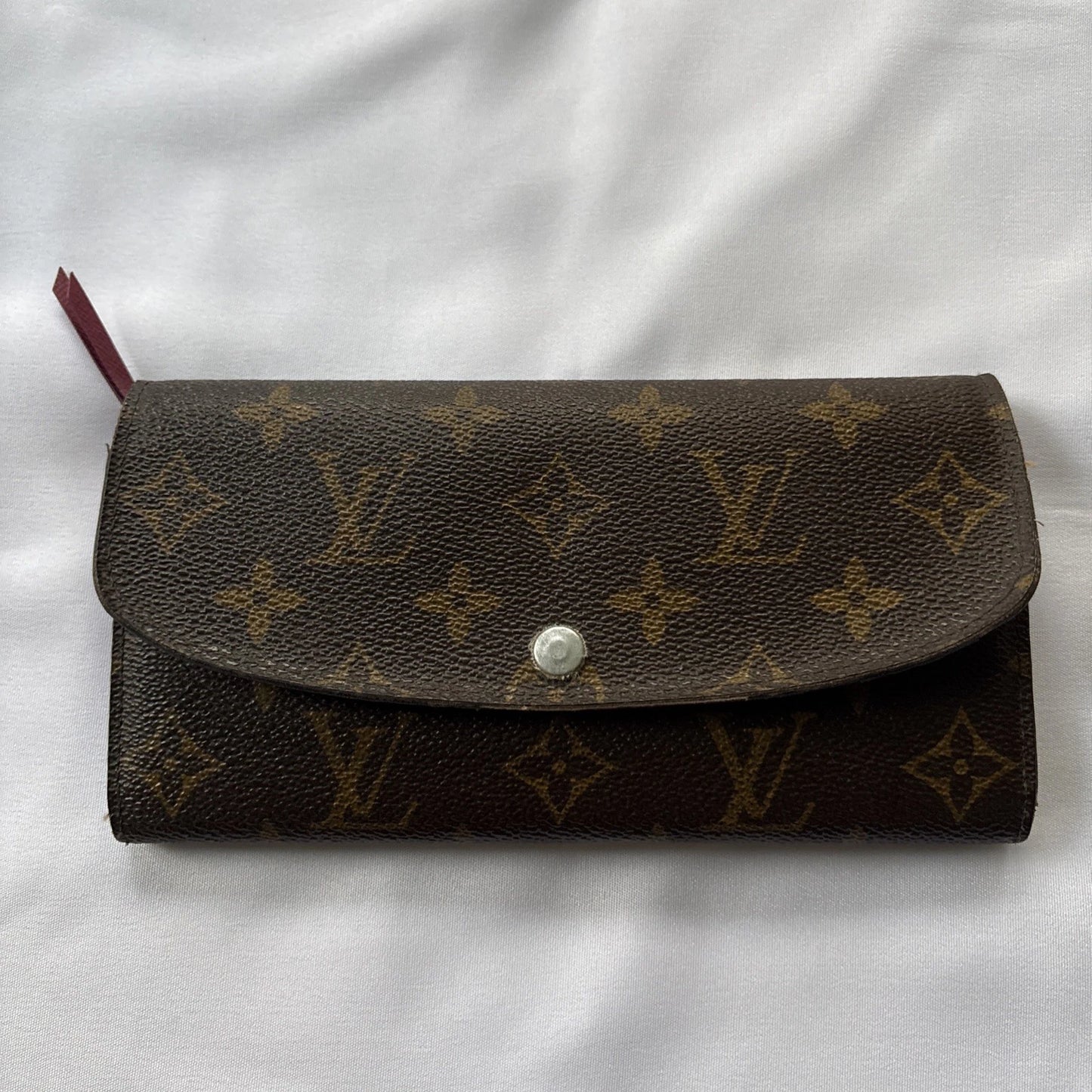 Brown wallet with monogram pattern on a white fabric background