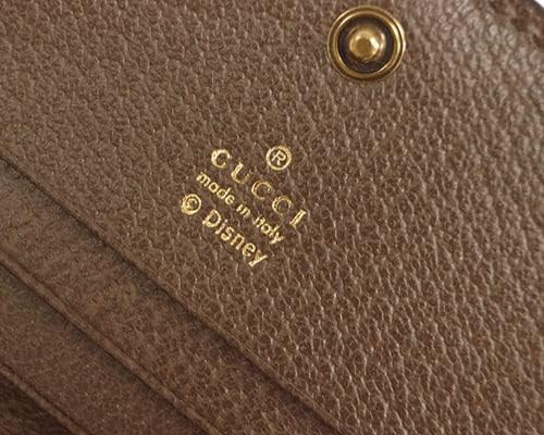 Close-up of a brown leather product with Gucci and Disney logos.