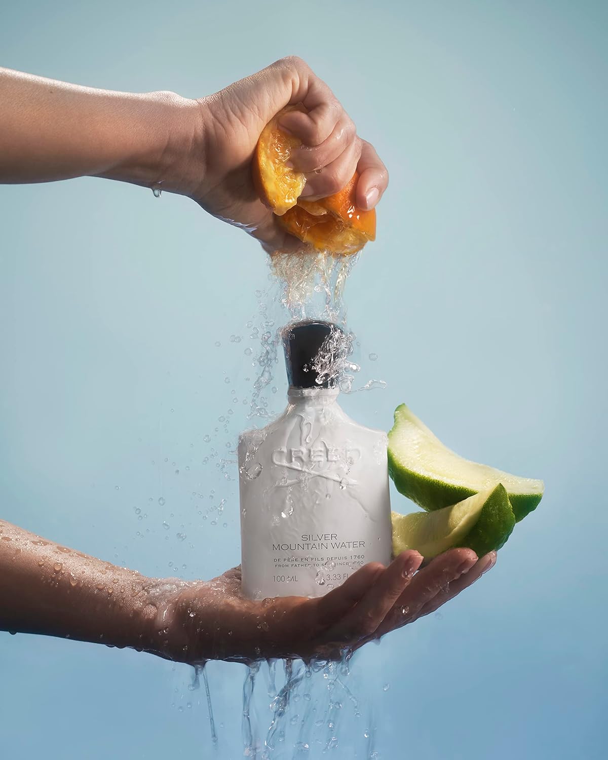 Person squeezing an orange into a bottle with water splashing out, against a clear blue sky.