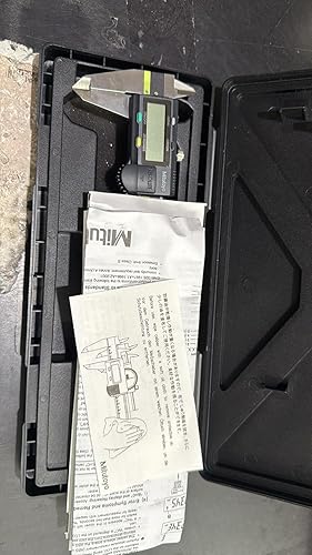Black tool case with digital caliper, manuals, and diagrams on a gray surface