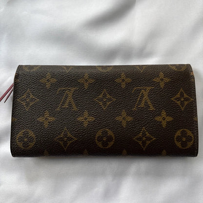 Brown leather wallet with monogram pattern on a white fabric background