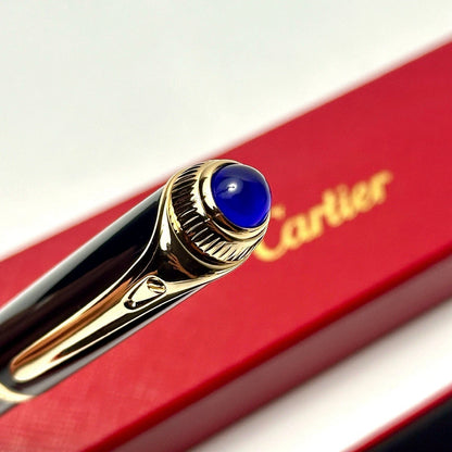 Gold pen with blue cap on a red Cartier box