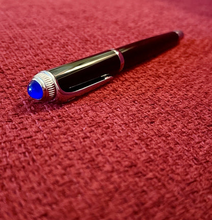 Pen with a blue accent on a red textured surface