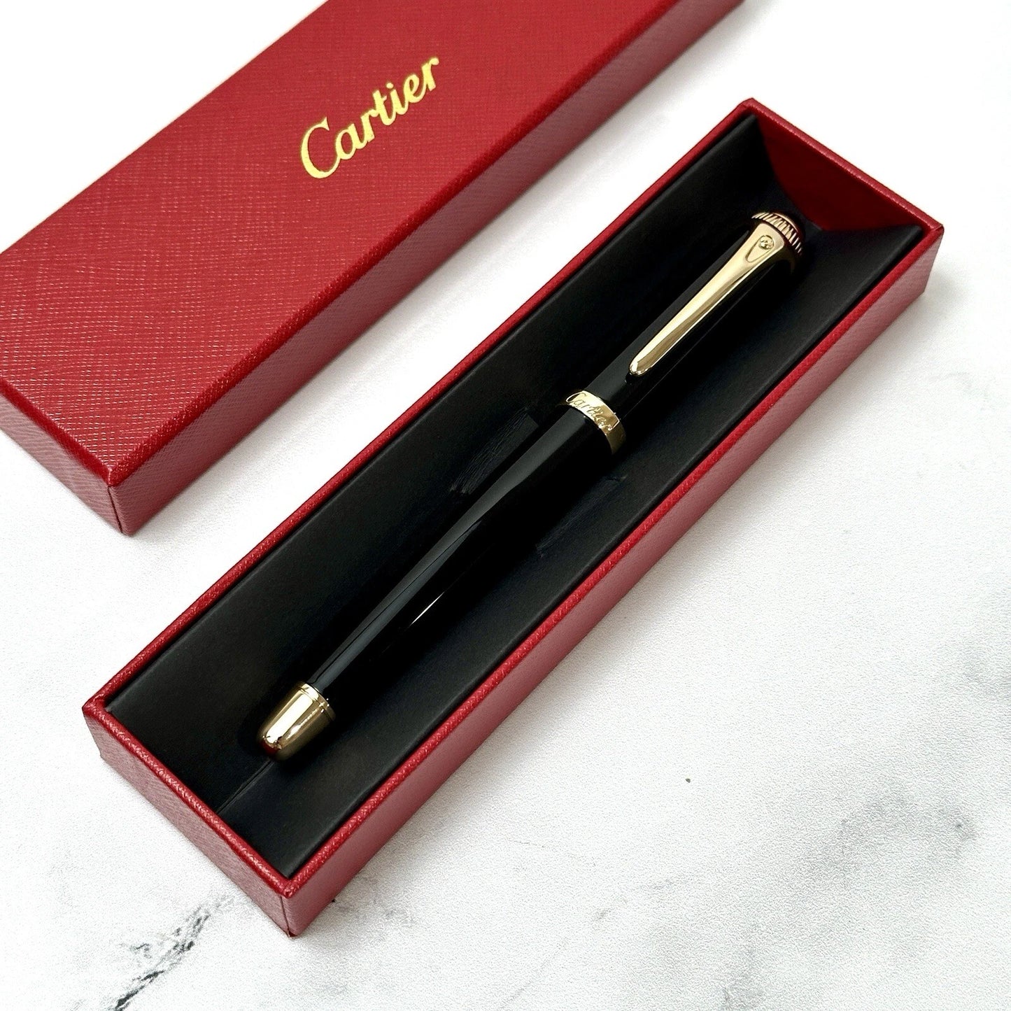 Cartier pen in a red box on a marble surface