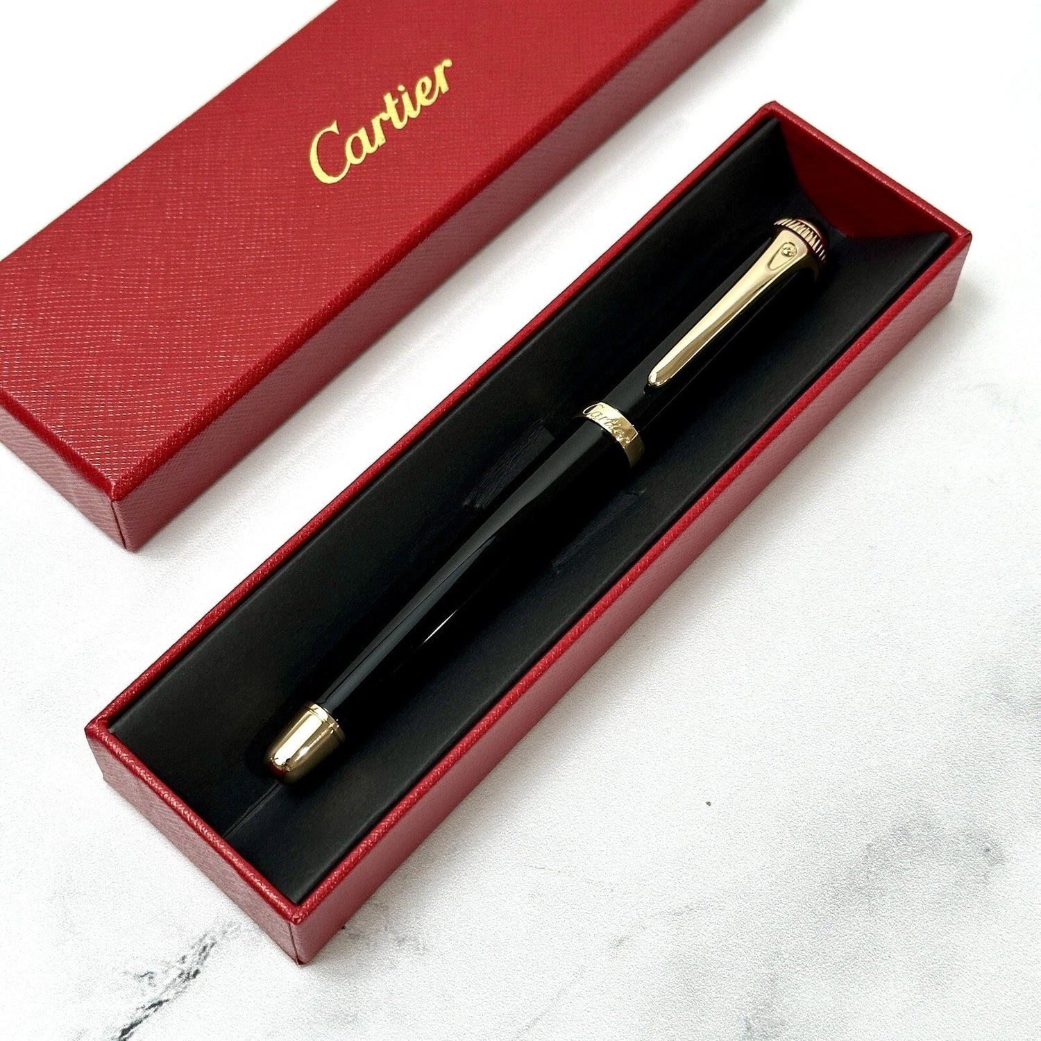 Cartier pen in a red box on a marble surface