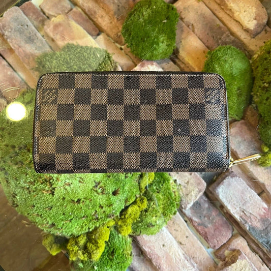 Checkered wallet on a decorative surface with green plants