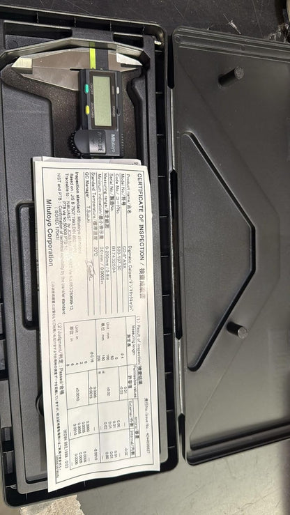 Digital caliper and manual inside a black case on a dark surface
