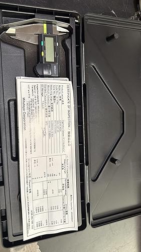 Digital caliper and manual inside a black case on a gray surface