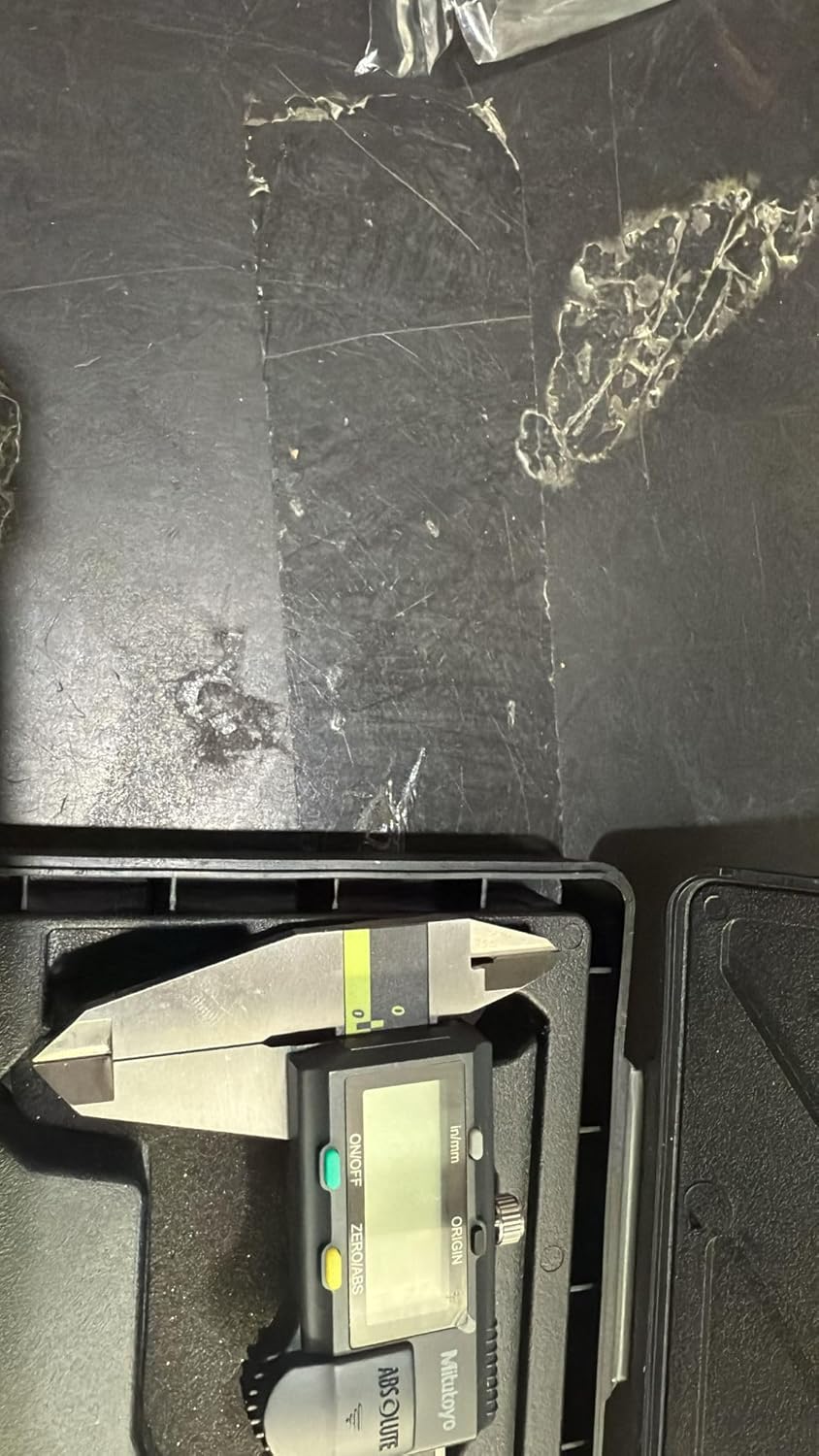 Digital caliper on a black surface with visible wear