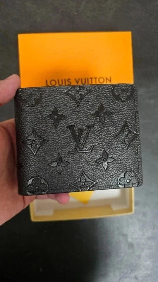 Louis Vuitton wallet held in front of a yellow box with 'Louis Vuitton' branding.