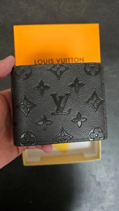 Louis Vuitton wallet held in front of a yellow box with 'Louis Vuitton' branding.