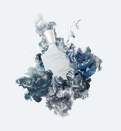 Perfume bottle with 'Creed' branding surrounded by icy crystal-like formations on a light gray background.