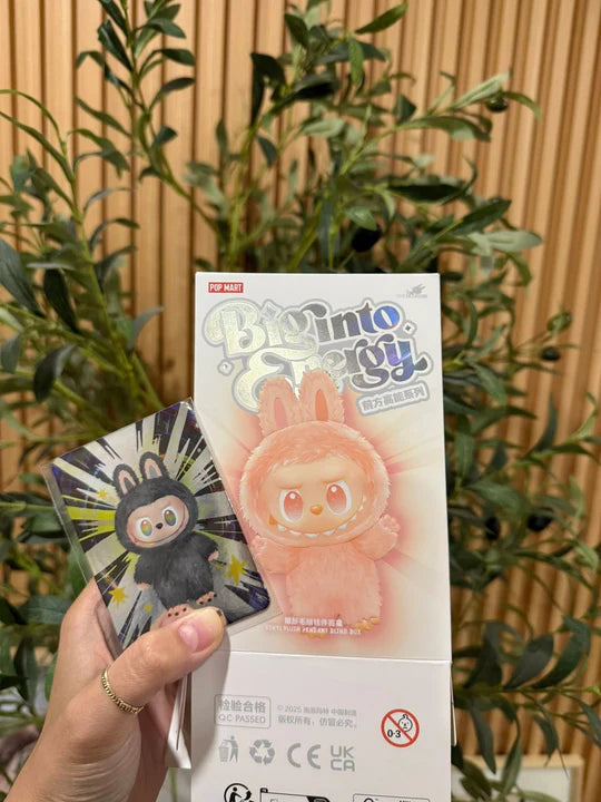 Product packaging with a character design held by a hand, against a natural background.