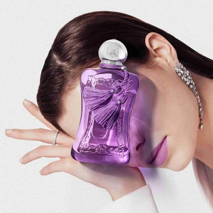 Purple perfume bottle held by a hand with a blurred background