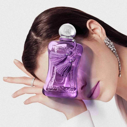 Purple perfume bottle held by a hand with a blurred background