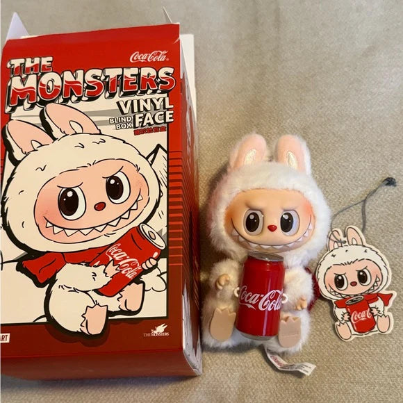 Vinyl figure of a character holding a Coca-Cola can next to its packaging